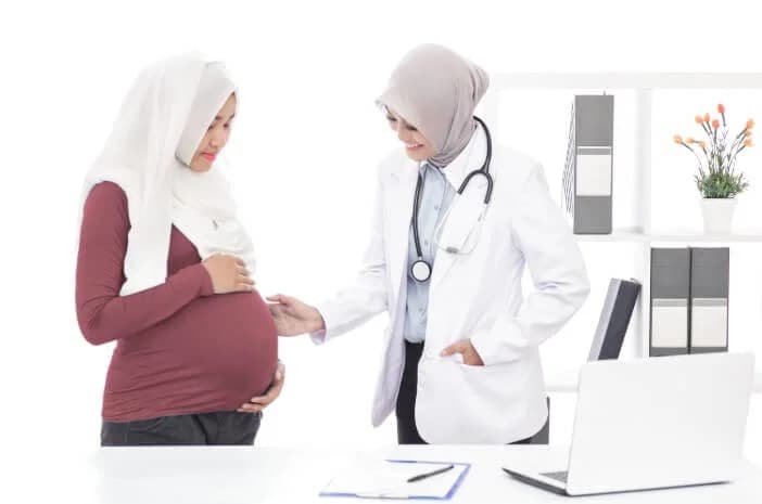 Seorang perempuan hamil sedang diperiksa oleh dokter di ruang praktik.